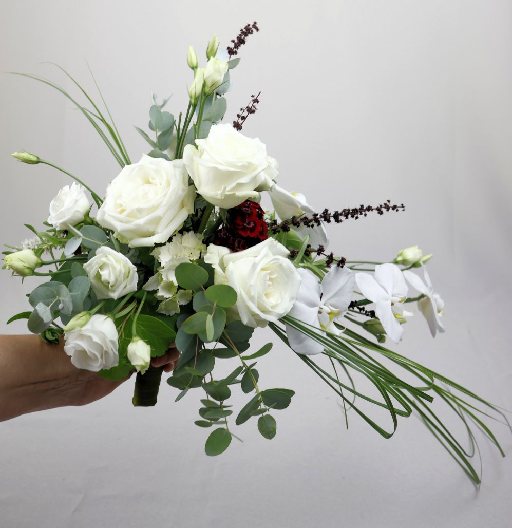 Een persoon houdt een boeket roze bruidsbloemen in zijn hand.