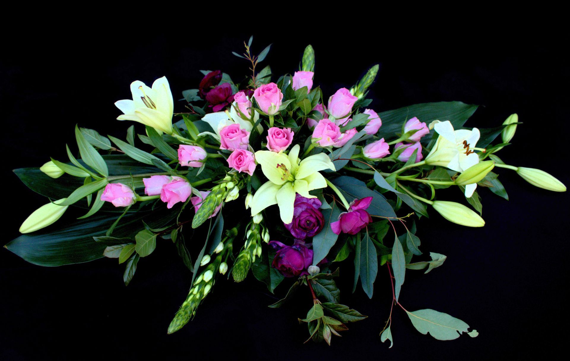 Een  bloemstuk van roze en witte bloemen op een zwarte achtergrond