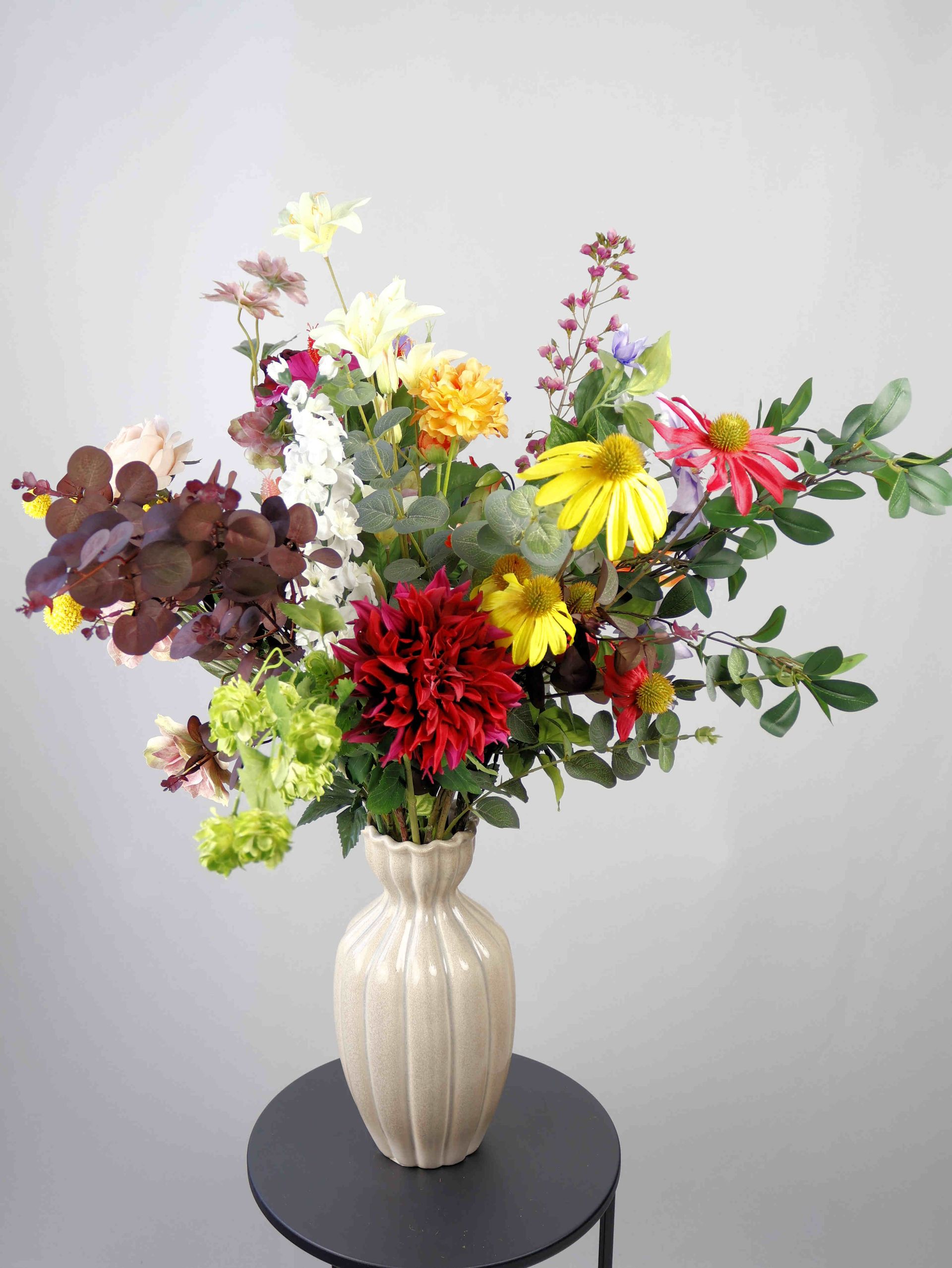 Op een tafel staat een vaas met niet van echt te onderscheiden zijdenbloemen.