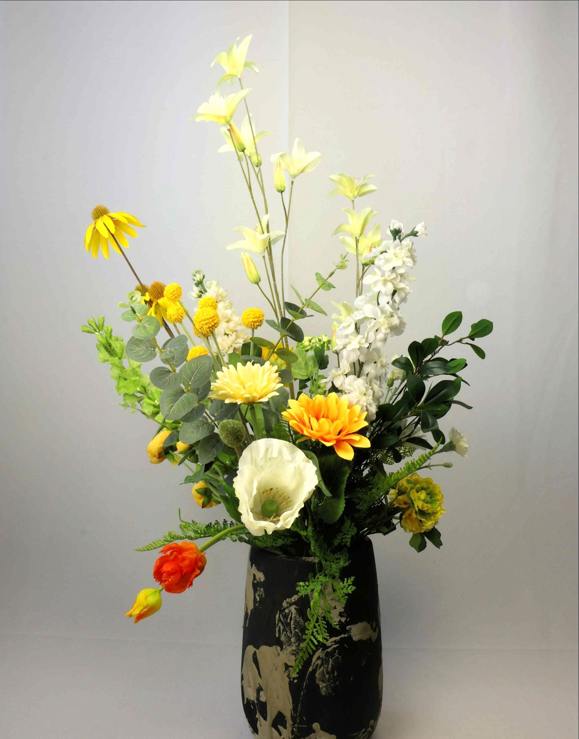 Een vaas gevuld met gele en witte bloemen op een tafel.