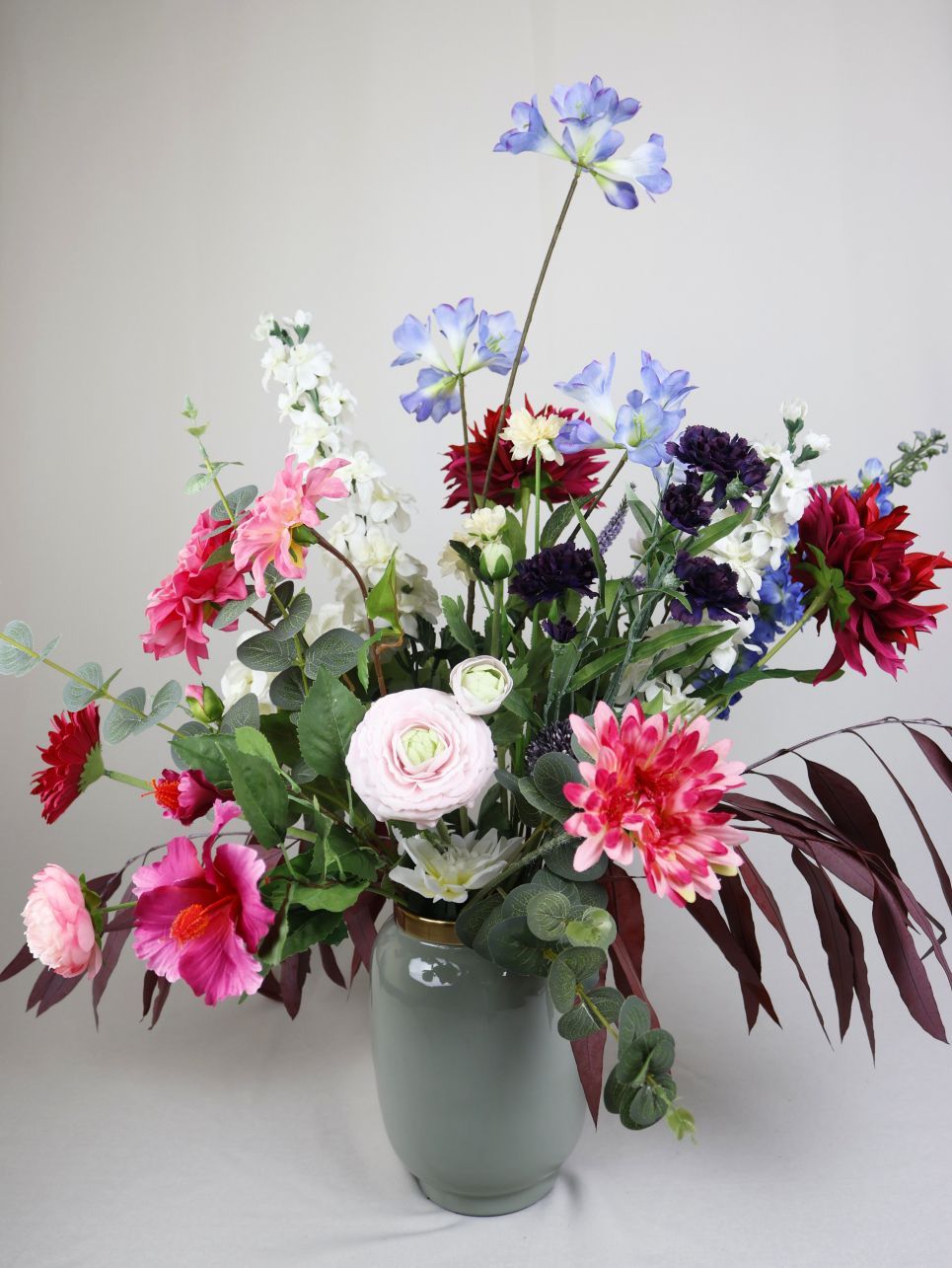 Op een tafel staat een vaas met zijden bloemen.