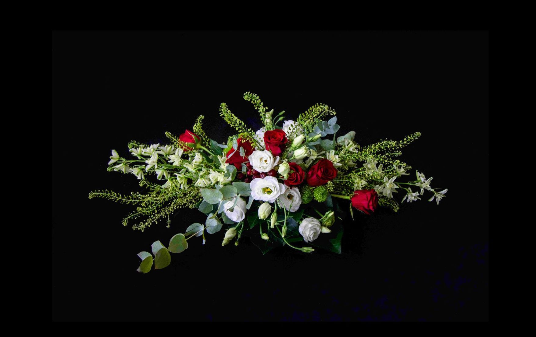 Een bloemstuk van rode en witte bloemen op een zwarte achtergrond