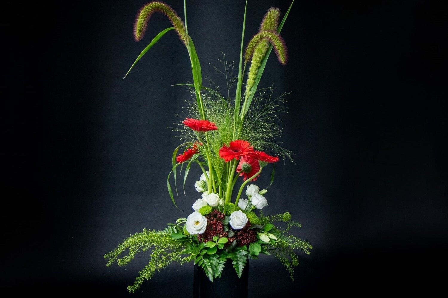 Een vaas gevuld met rode en witte bloemen op een zwarte achtergrond