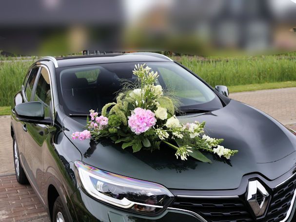 Groene auto versierd met bruidsbloemen.