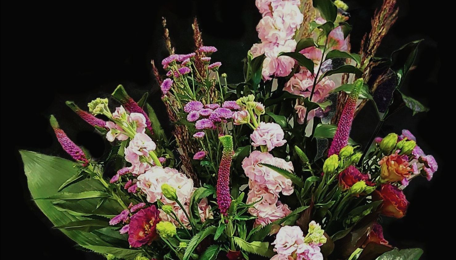 A bouquet of pink and purple flowers on a black background