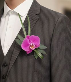 Man in grijs pak met een roze orchidee als boutonnière.