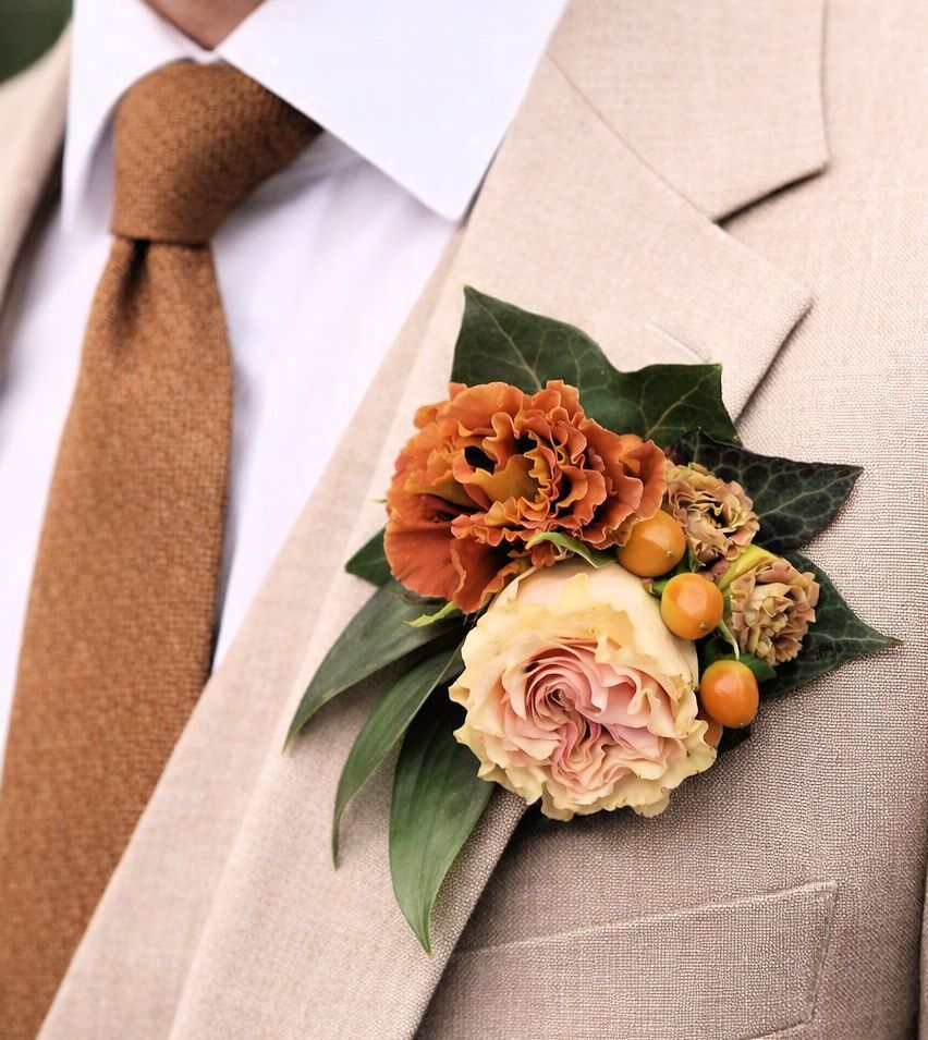 Man in beige pak met oranje boutonnière en bijpassende stropdas.