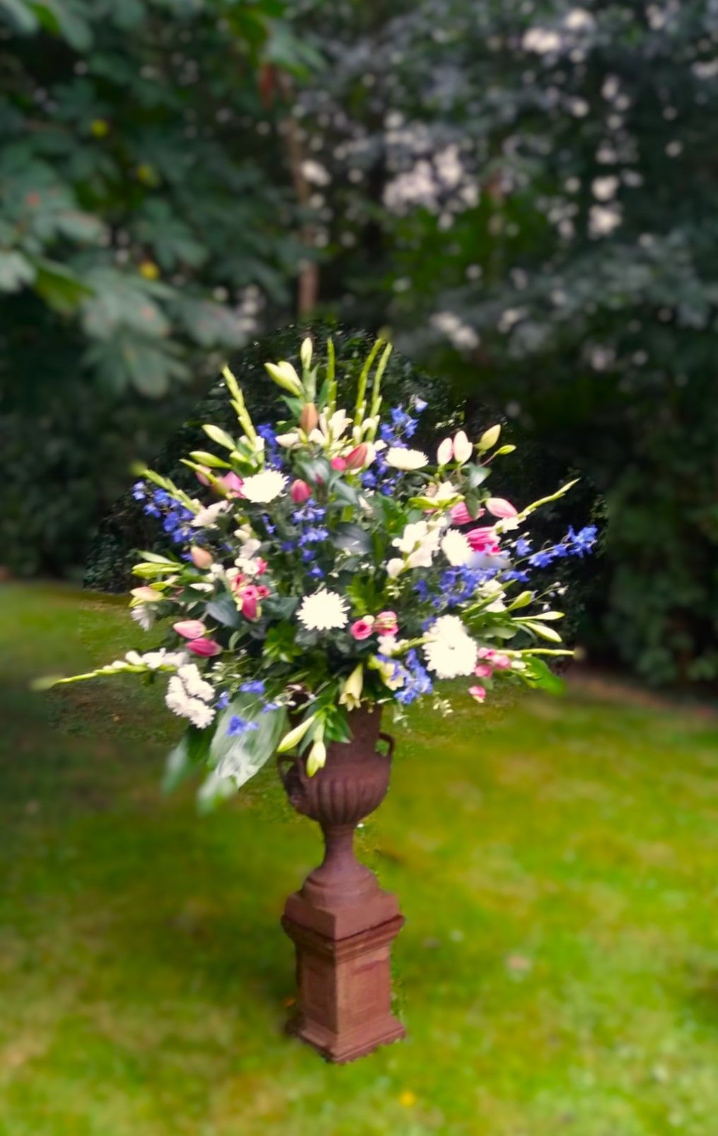 Een grote vaas gevuld met bloemen staat op een weelderig groen veld.