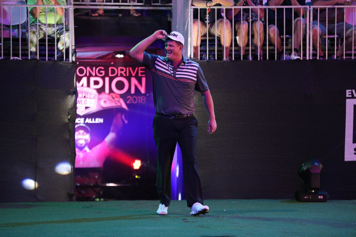 A man is standing on a golf course in front of a crowd.