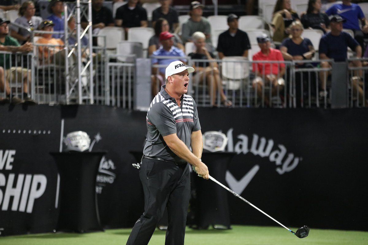 A man is swinging a golf club on a golf course