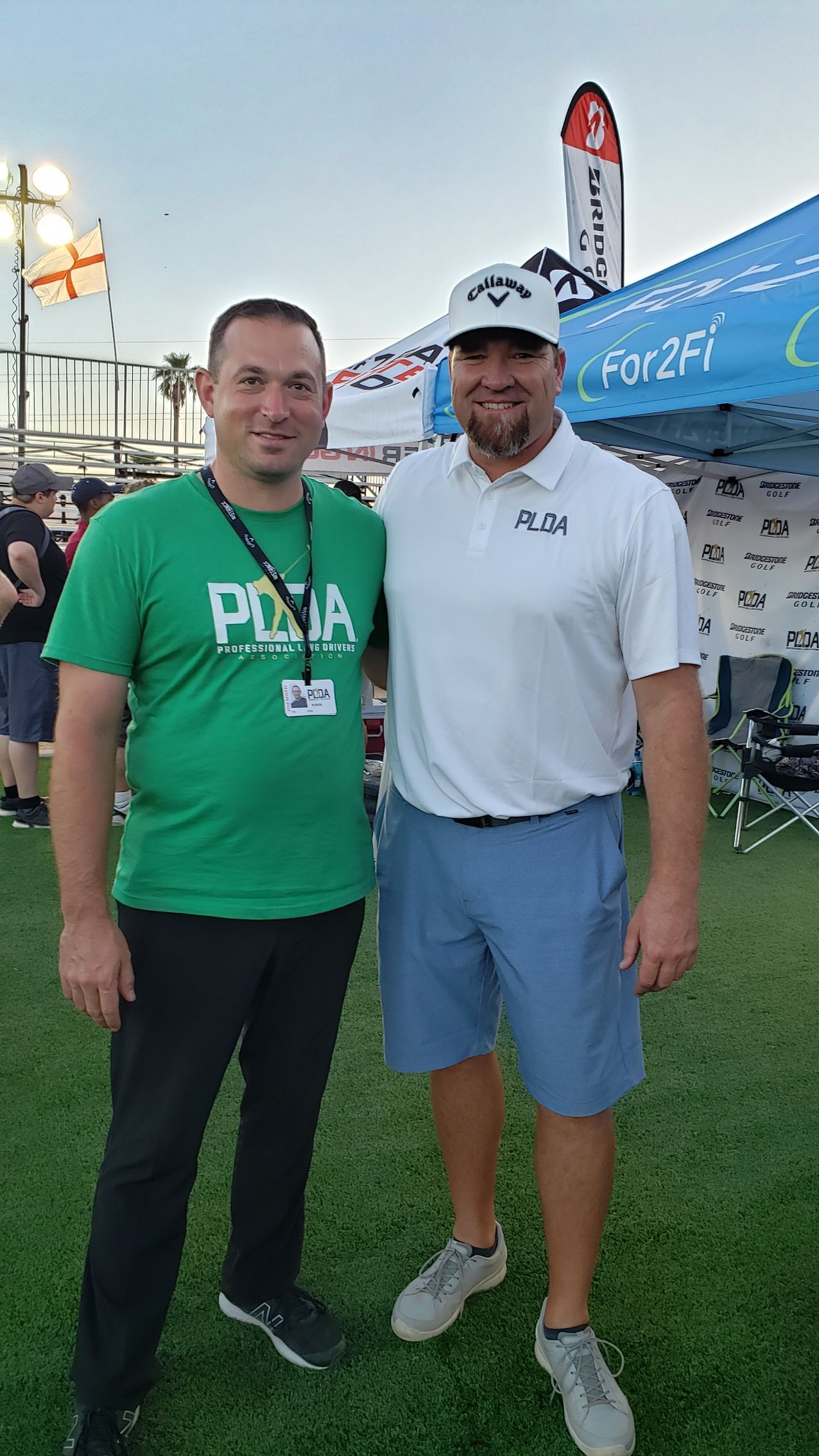 Two men are standing next to each other on a grassy field.