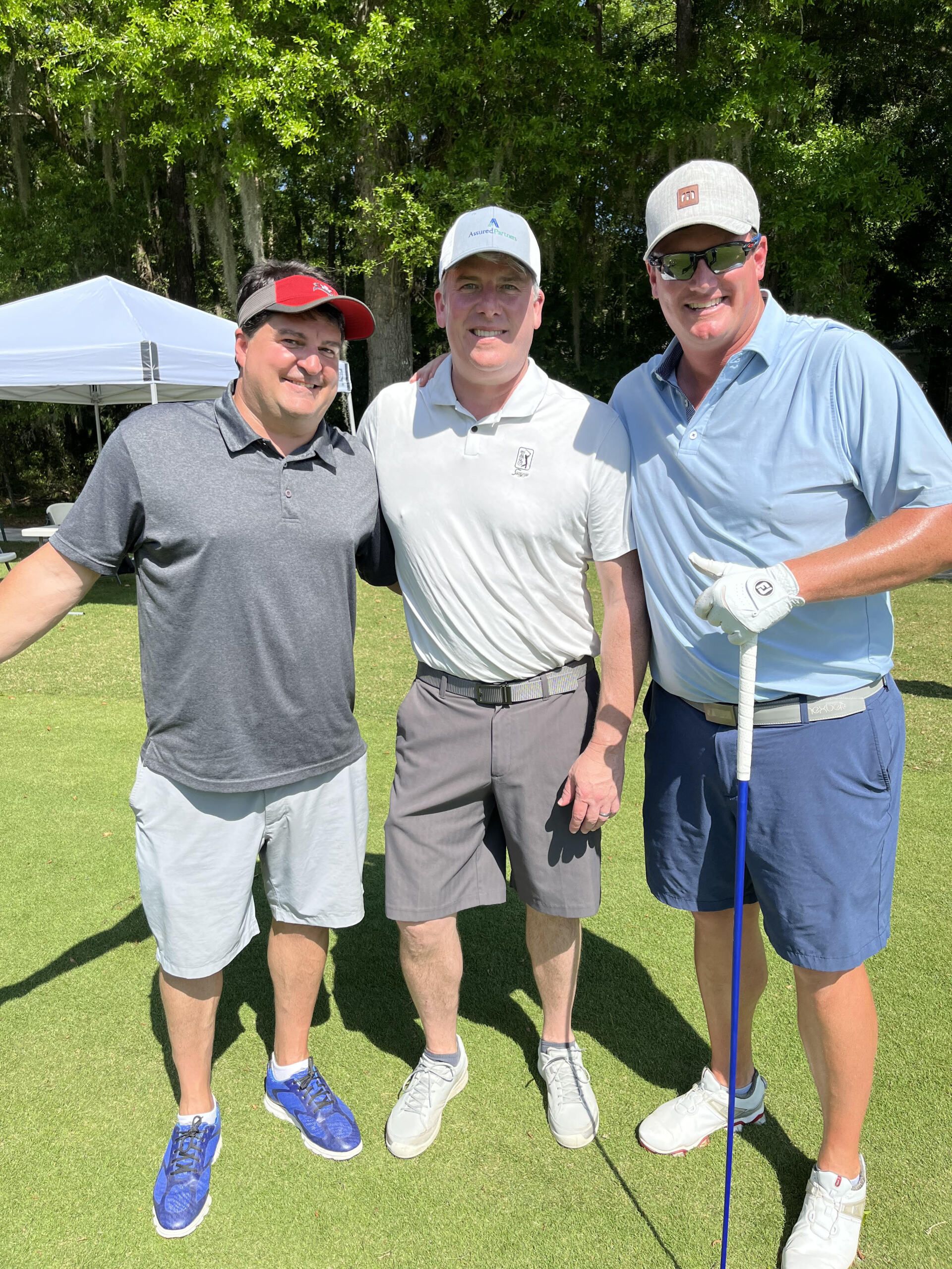 Three men are posing for a picture on a golf course.