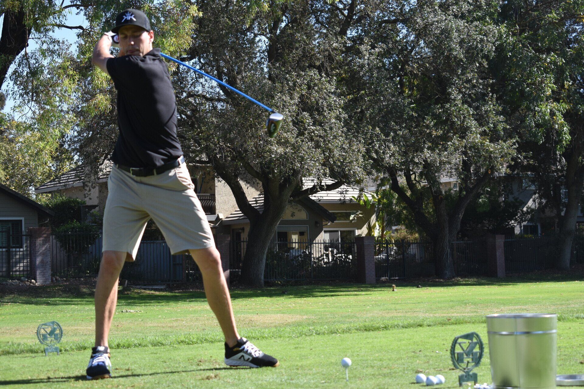 A man is swinging a golf club on a golf course.