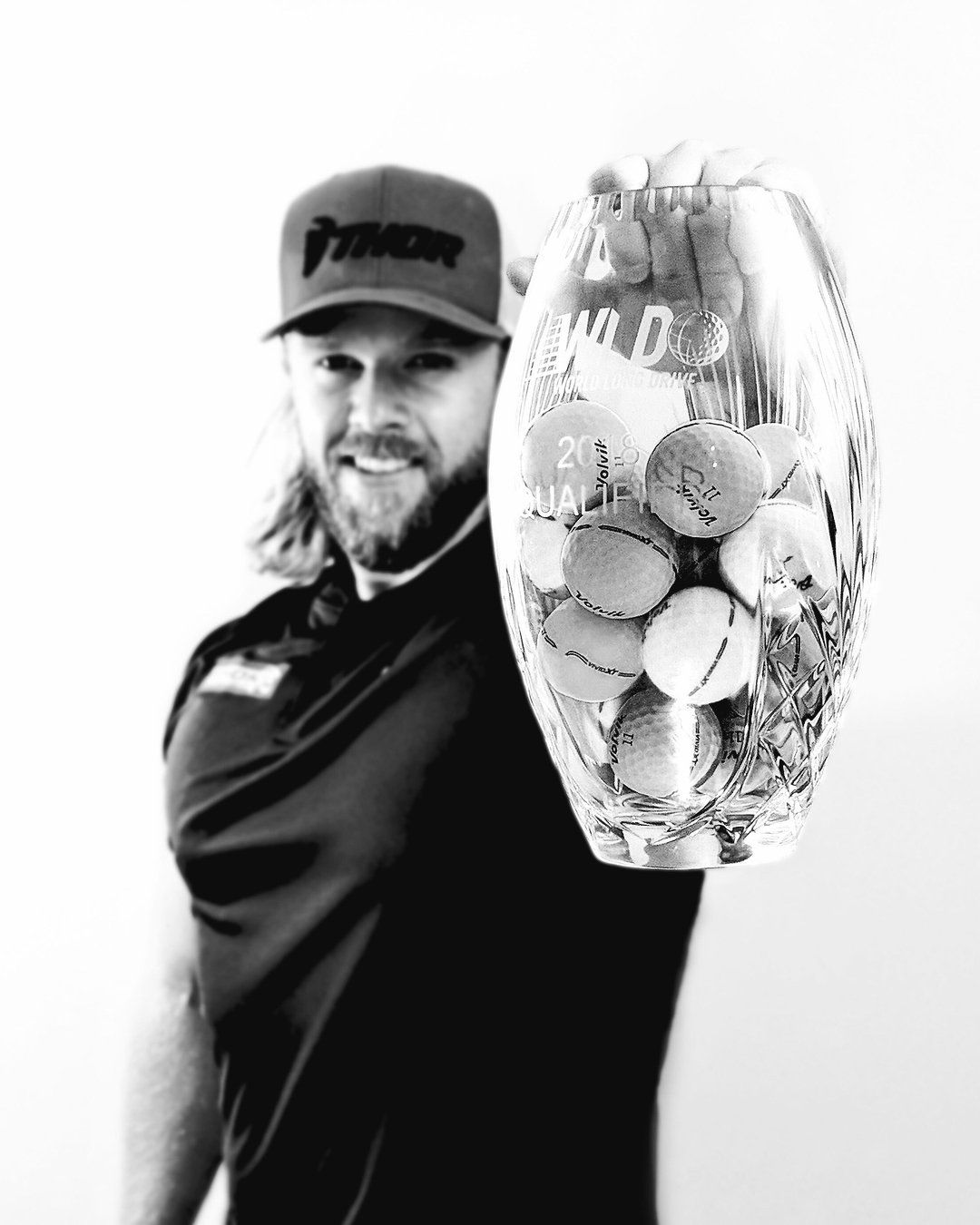 A man in a hat is holding a glass filled with golf balls.