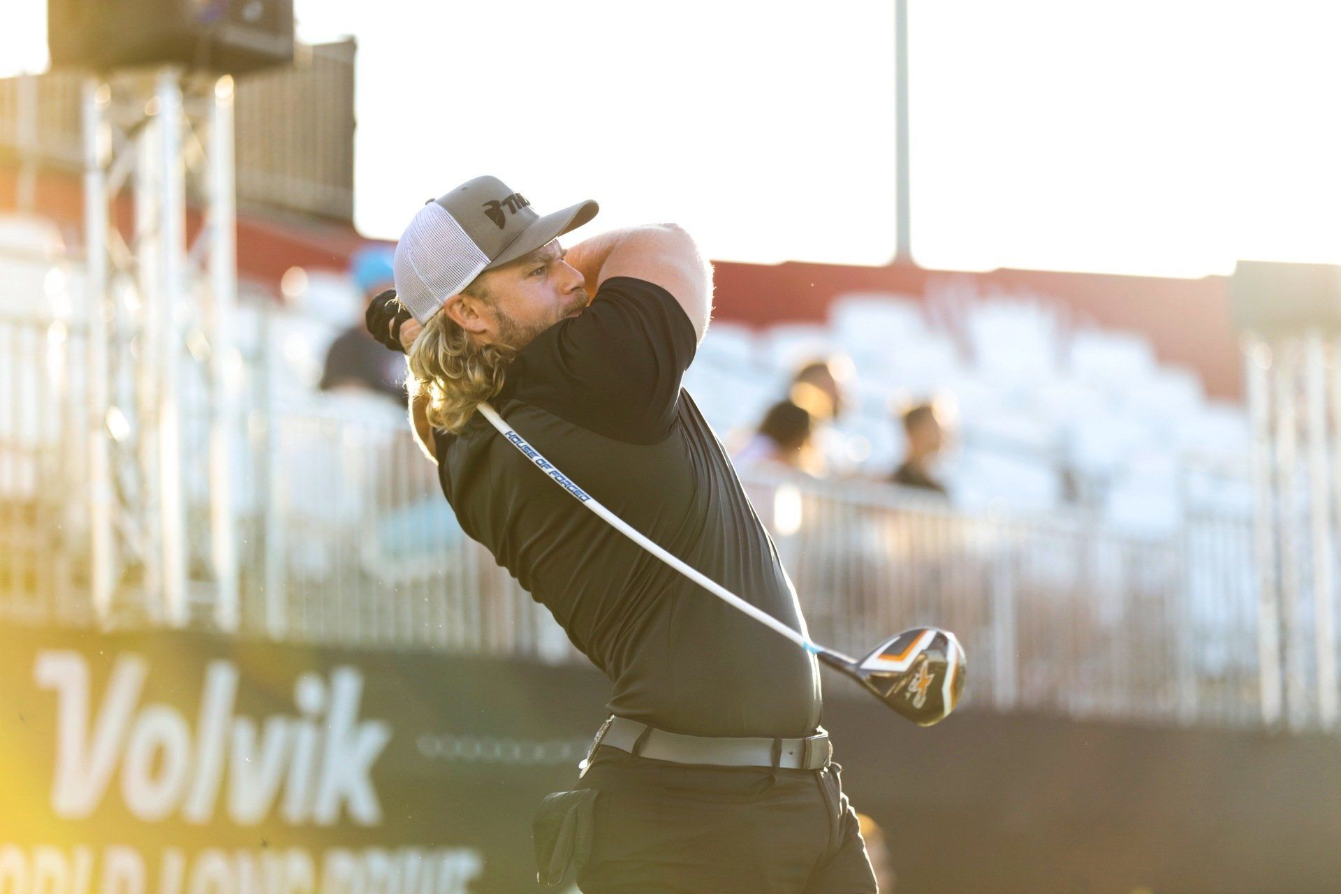A man is swinging a golf club on a golf course.