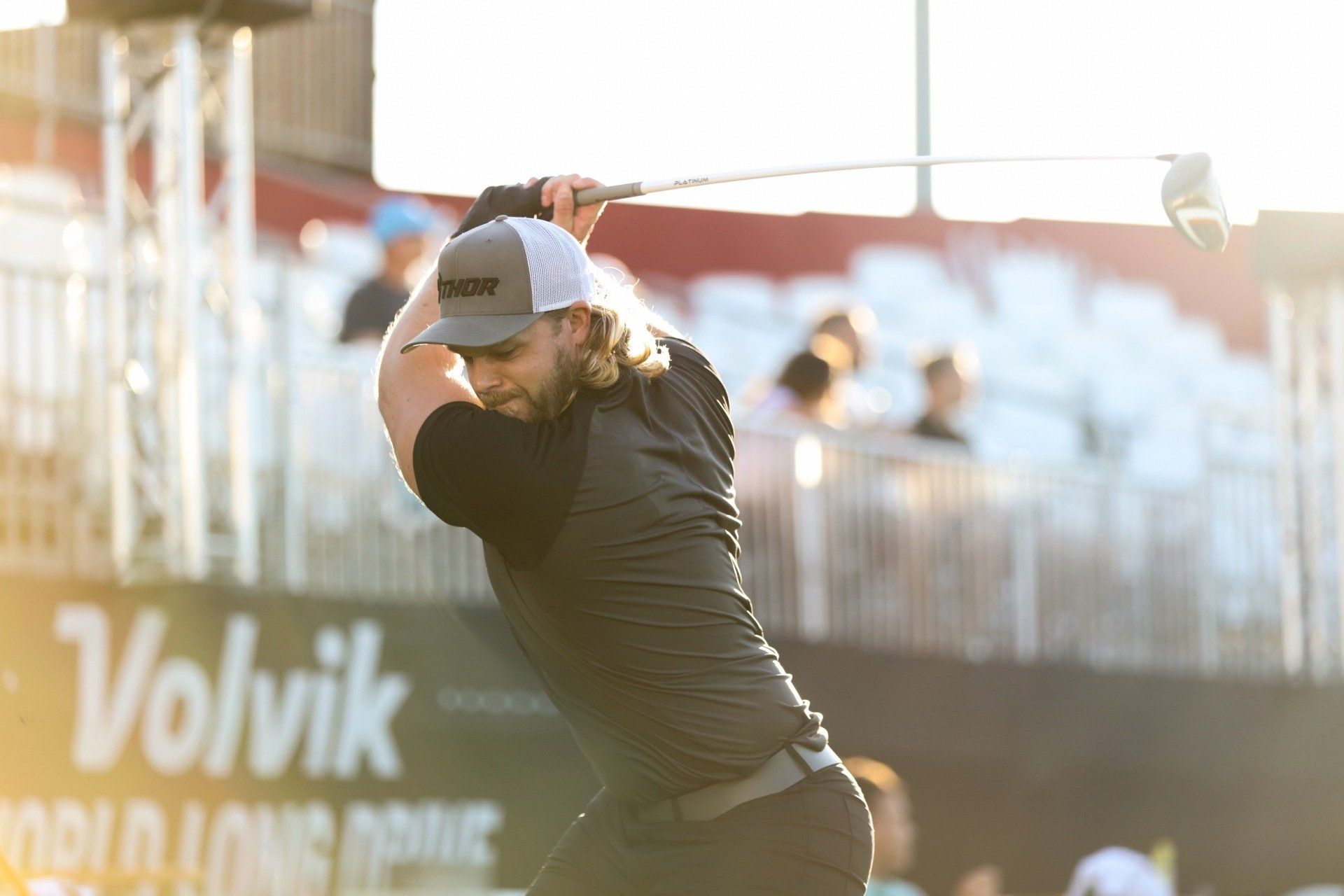 A man is swinging a golf club on a golf course.