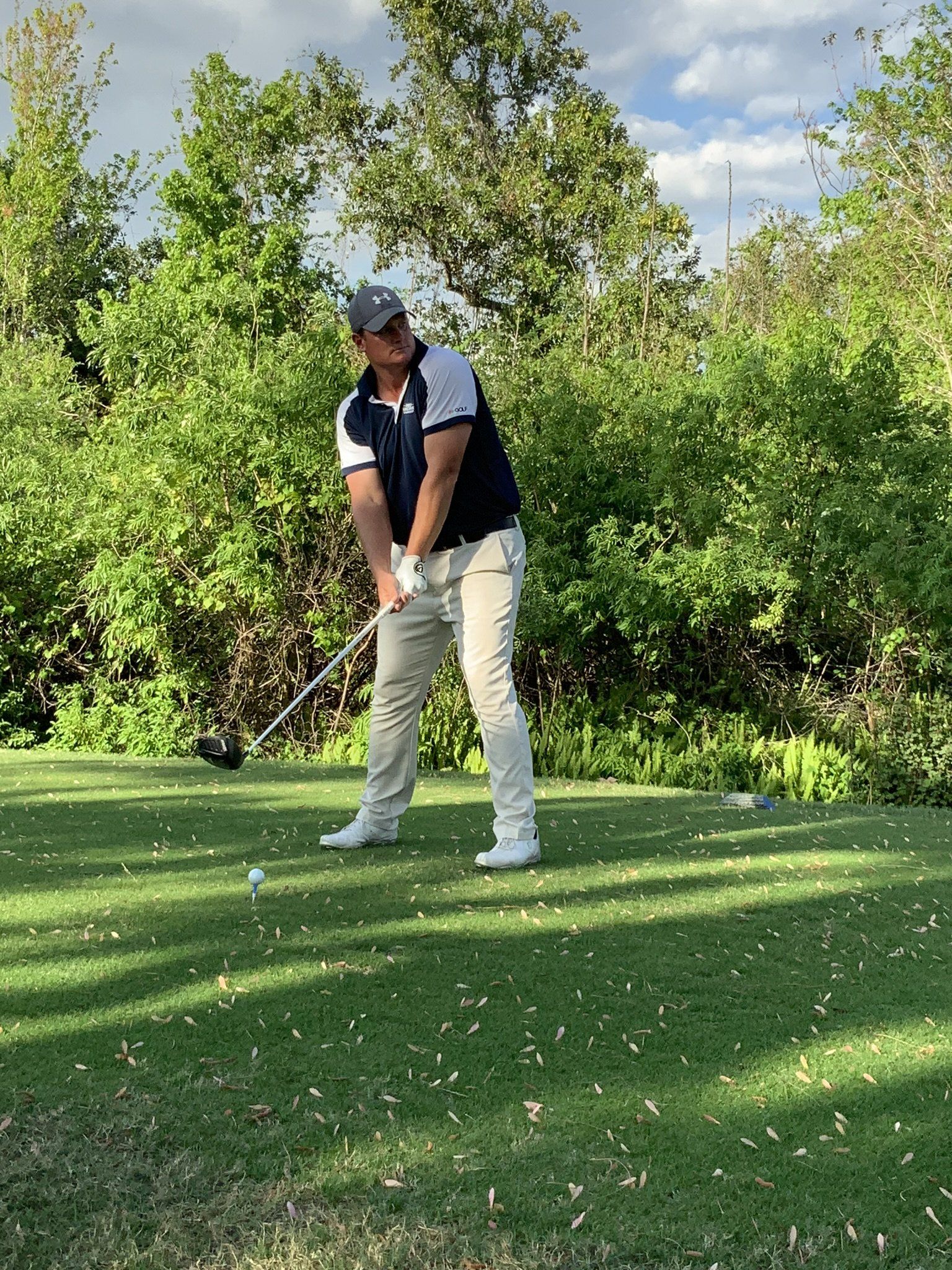A man is swinging a golf club on a golf course.