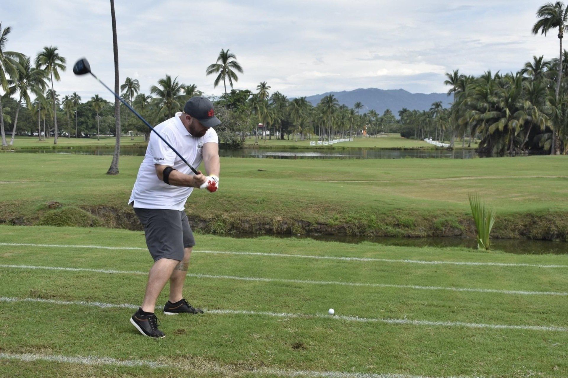 A man is swinging a golf club on a golf course.