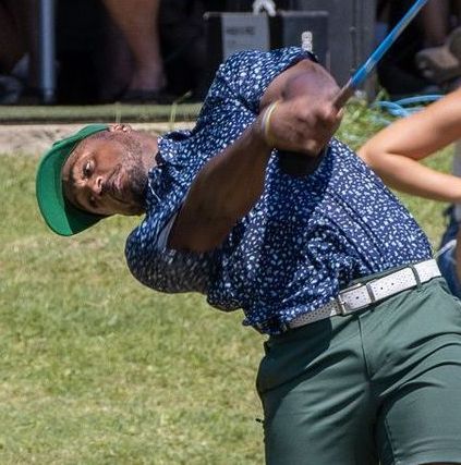 A man wearing a green hat is swinging a golf club