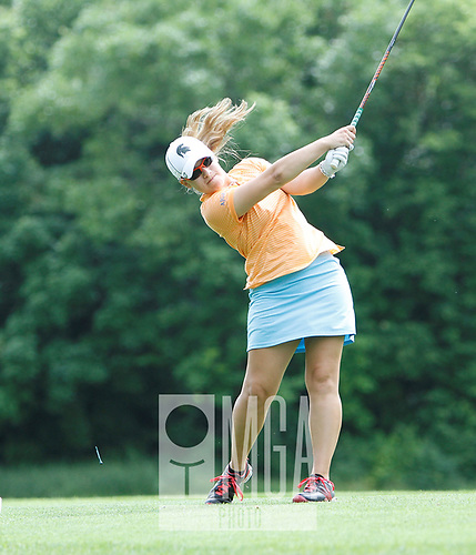 A woman is swinging a golf club on a golf course
