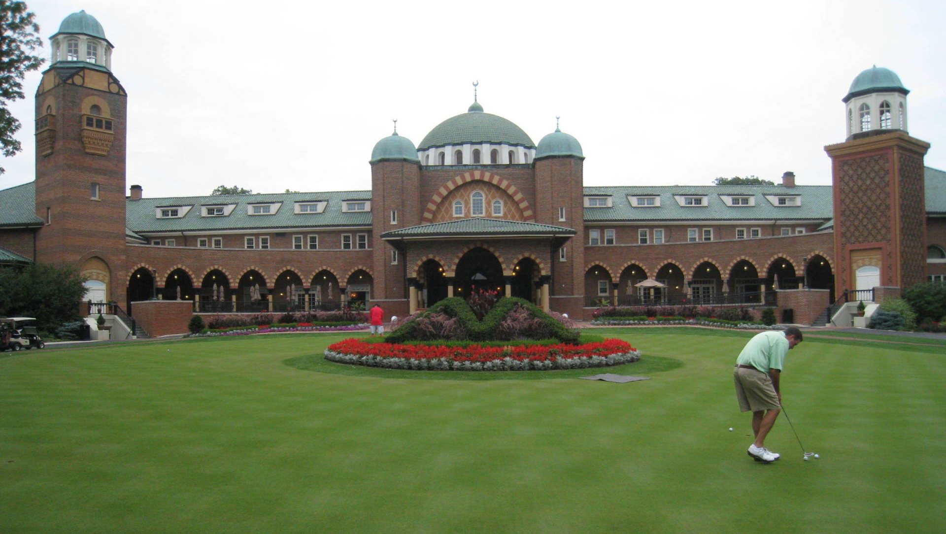 A man is playing golf in front of a large brick building