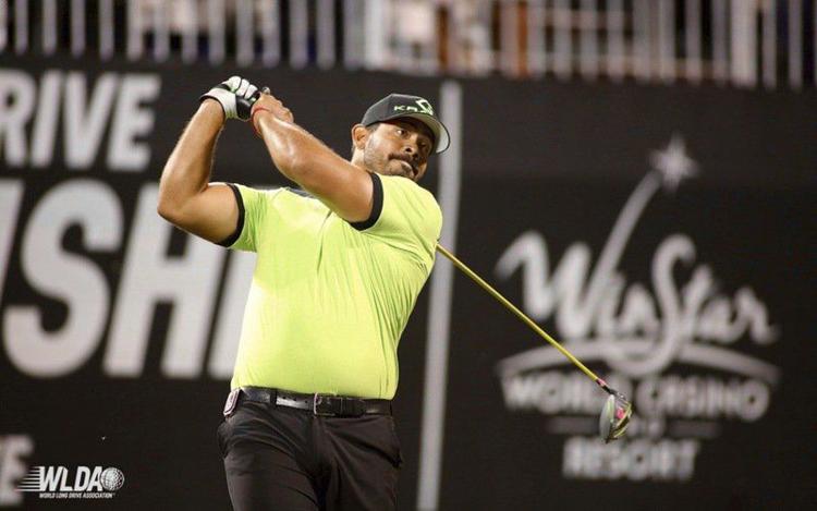 A man in a yellow shirt is swinging a golf club.