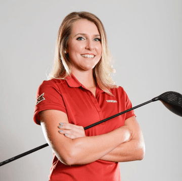 A woman in a red shirt is holding a golf club