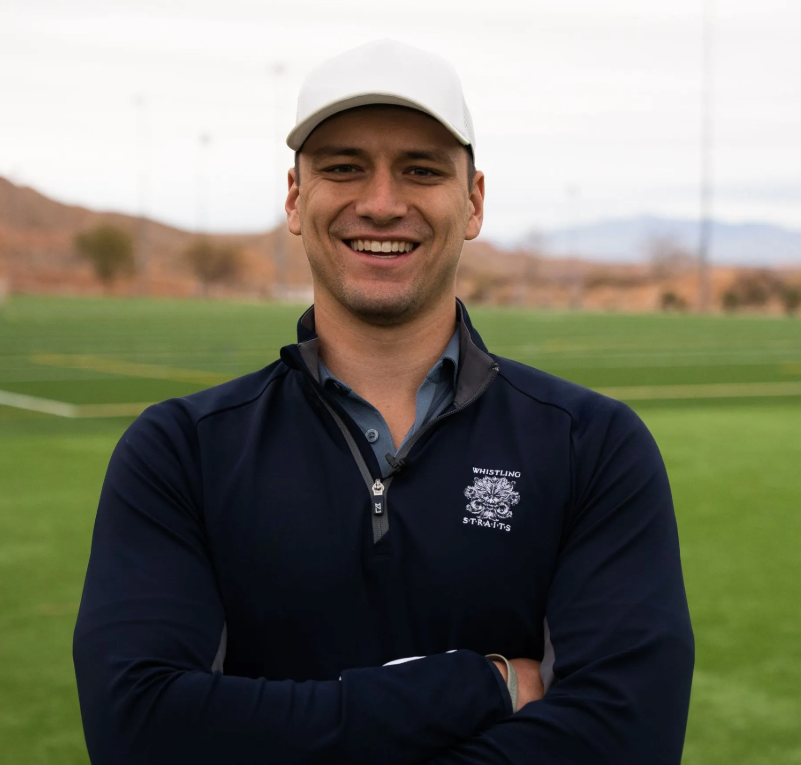 A man wearing a white hat and a blue sweater smiles for the camera