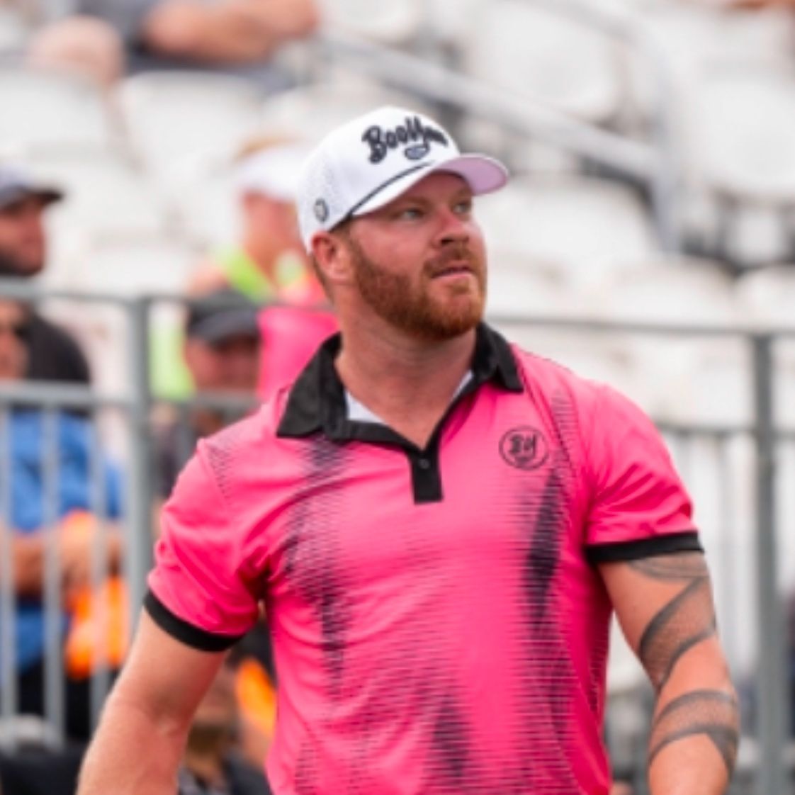 A man wearing a pink shirt and a white hat with the word bank on it