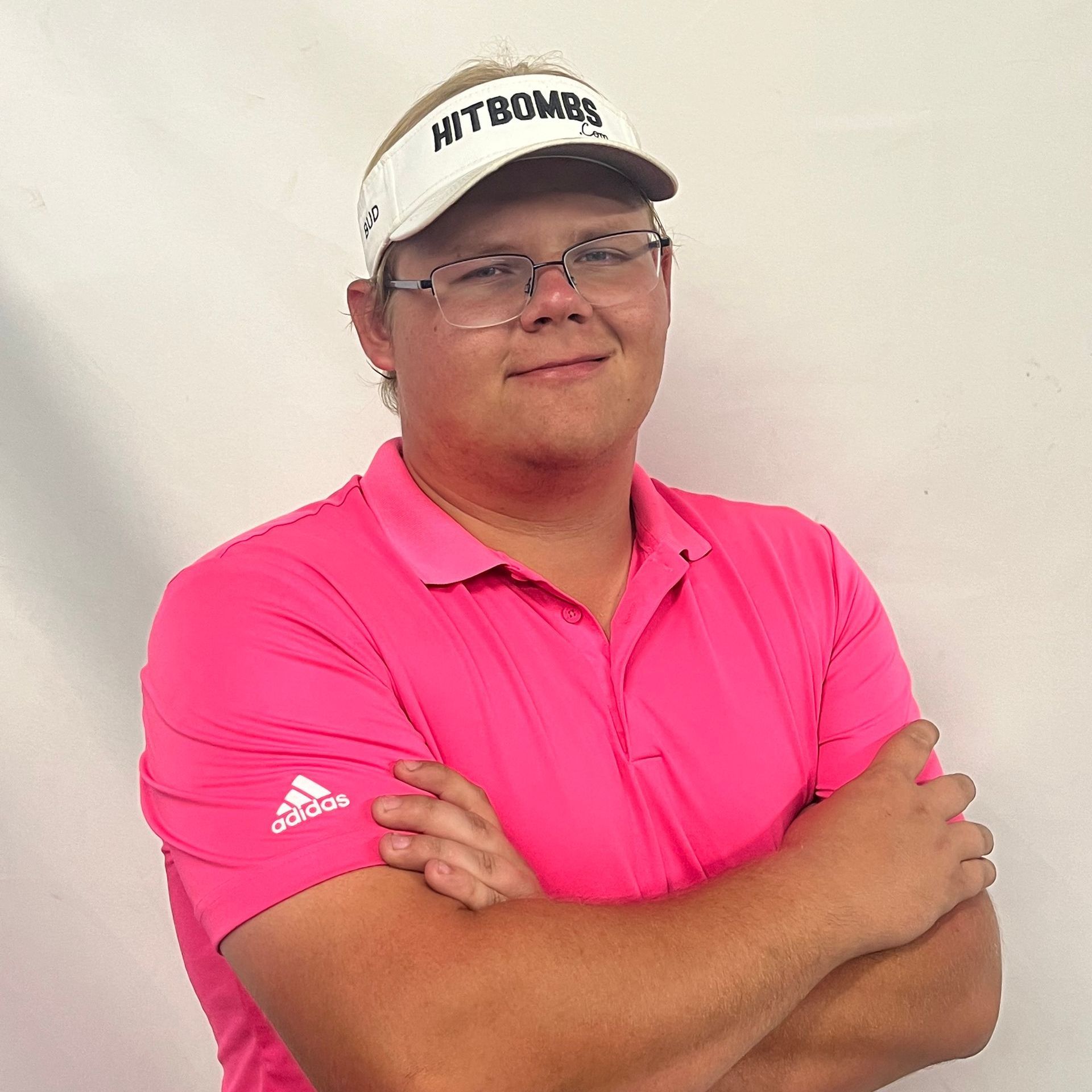 A man wearing a pink shirt and a white hat with the word hitbomber on it