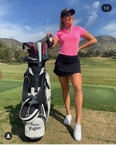 A woman is standing next to a golf bag on a golf course.