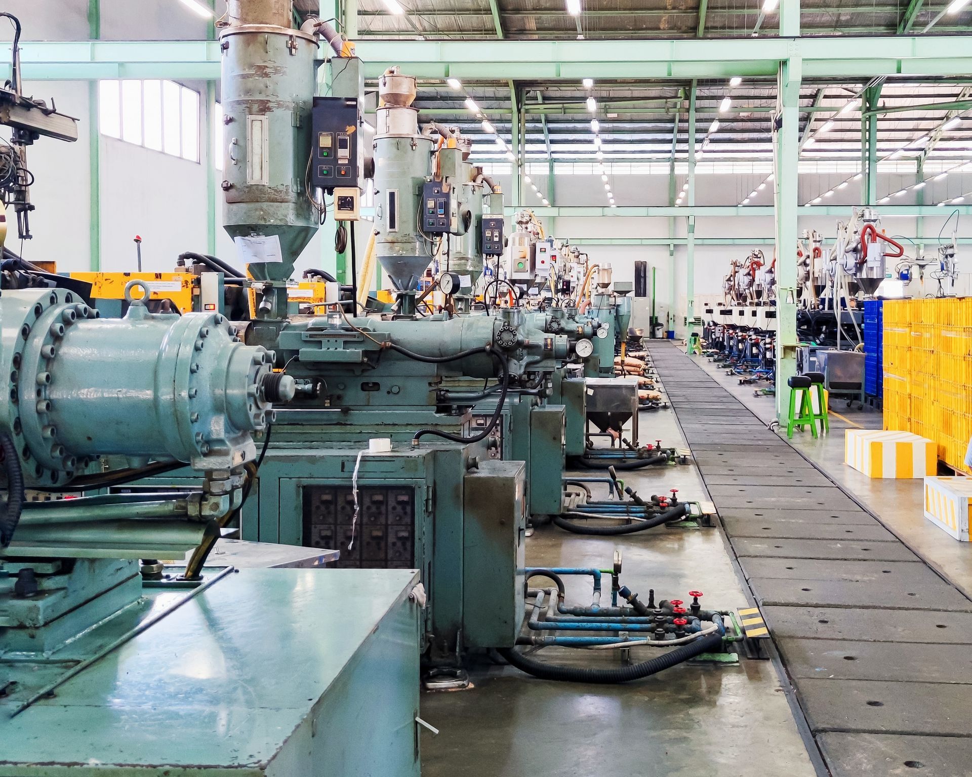 Factory floor with rows of industrial machinery; gray and yellow colors.