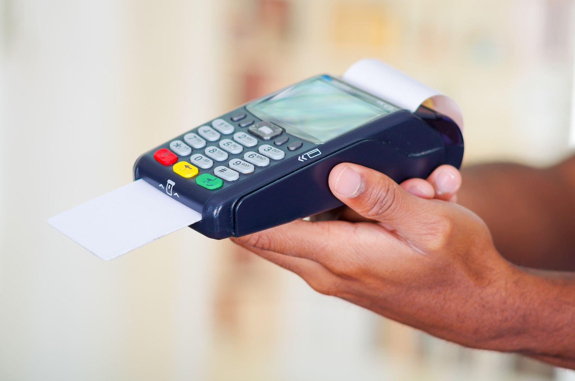 Person holding a credit card reader; a card is inserted, ready to be processed.