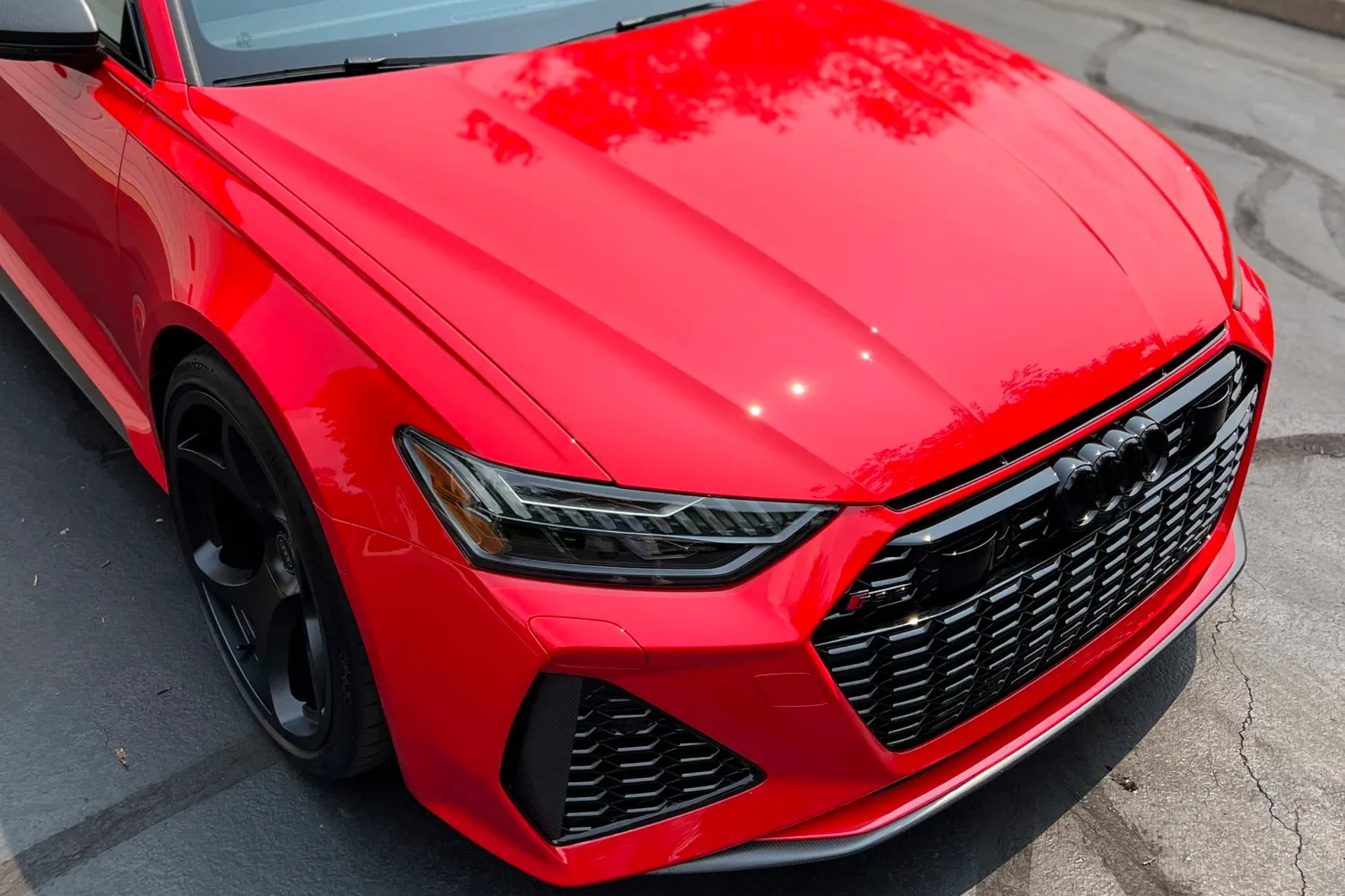 Red sports car front end in bright red with black grille, parked on pavement