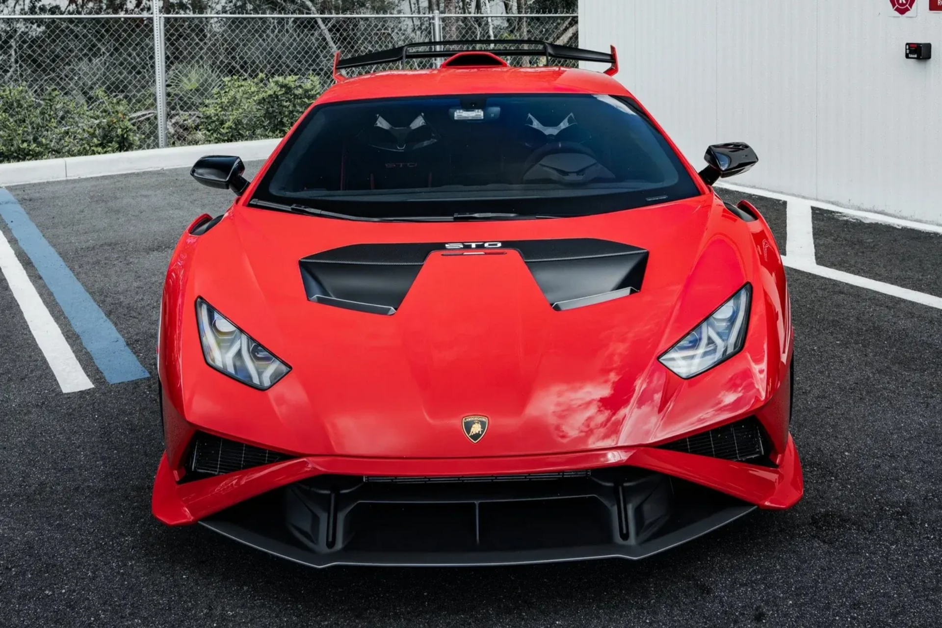 Front view of a red Lamborghini parked on wet pavement in a lot