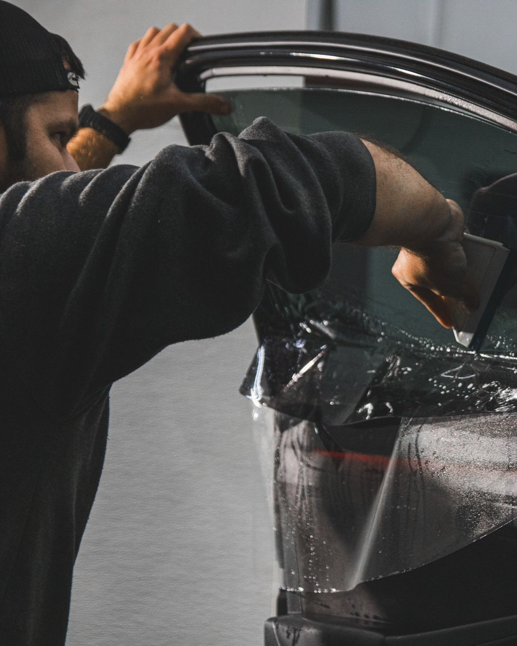 Person opening a car door and peeling off protective plastic from the interior.