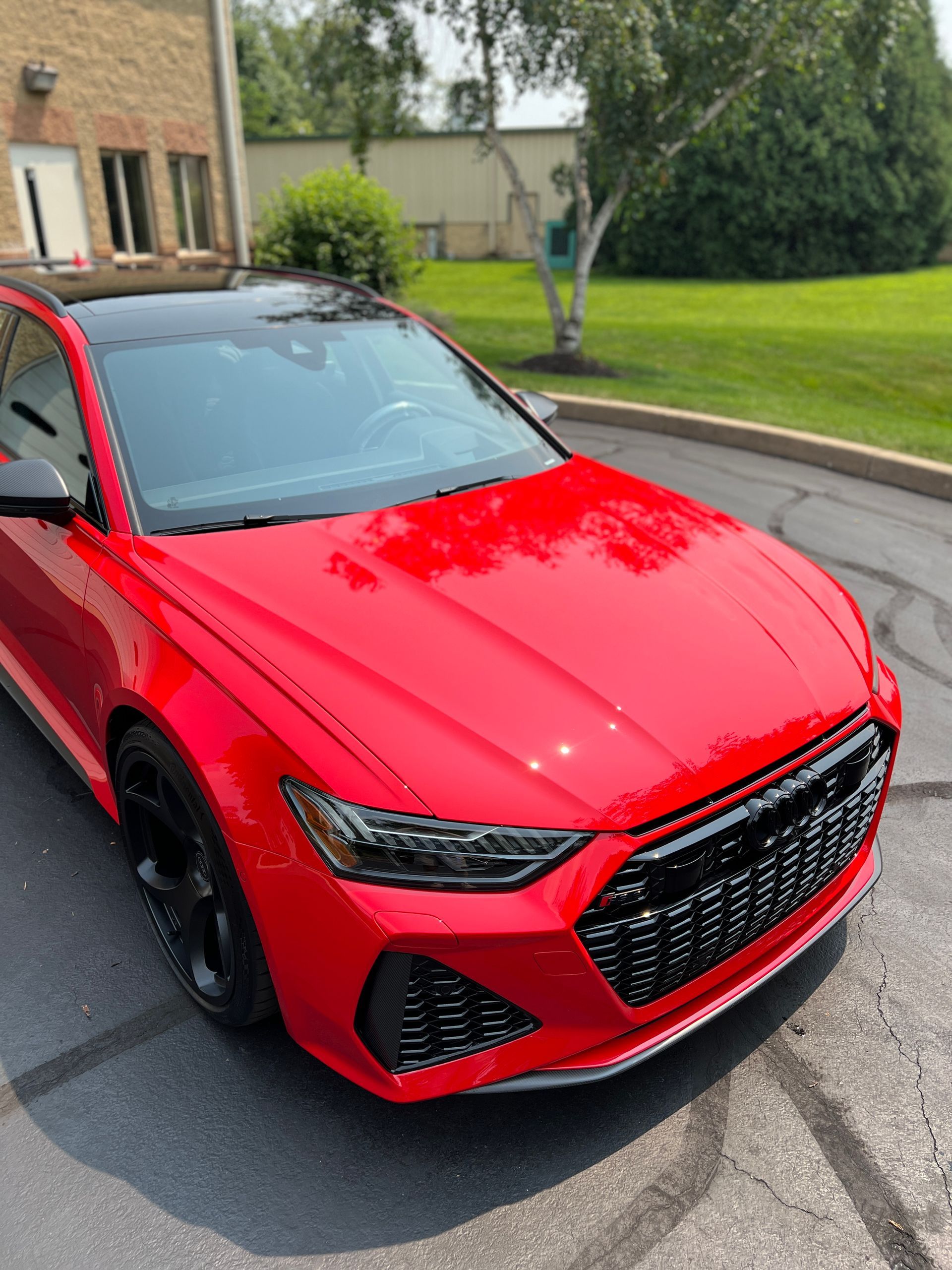 Red compact SUV parked on a wet driveway beside a lawn and house