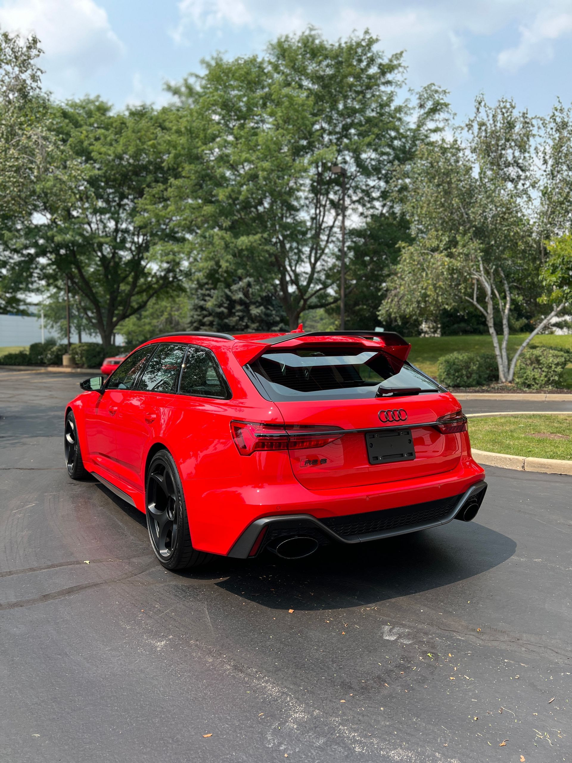 Red sports SUV parked on wet pavement with trees and a cloudy sky in the background