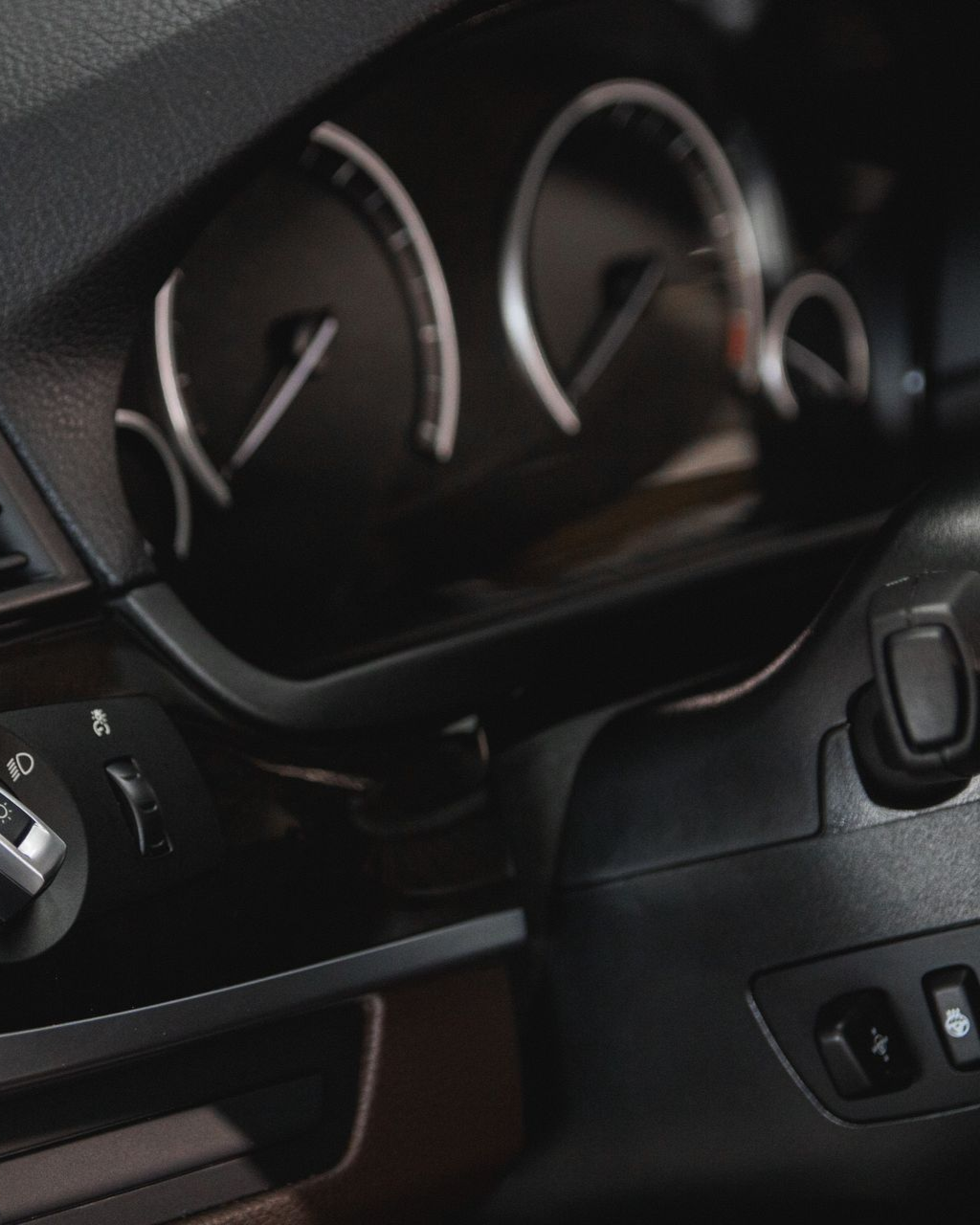 Close-up of a car dashboard with speedometer gauges, steering wheel, and control buttons
