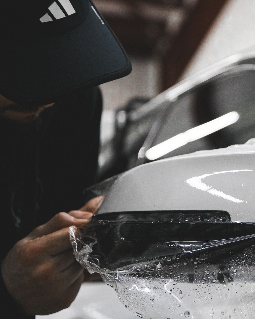 Person hand-polishing a white car headlight with a cloth in a garage
