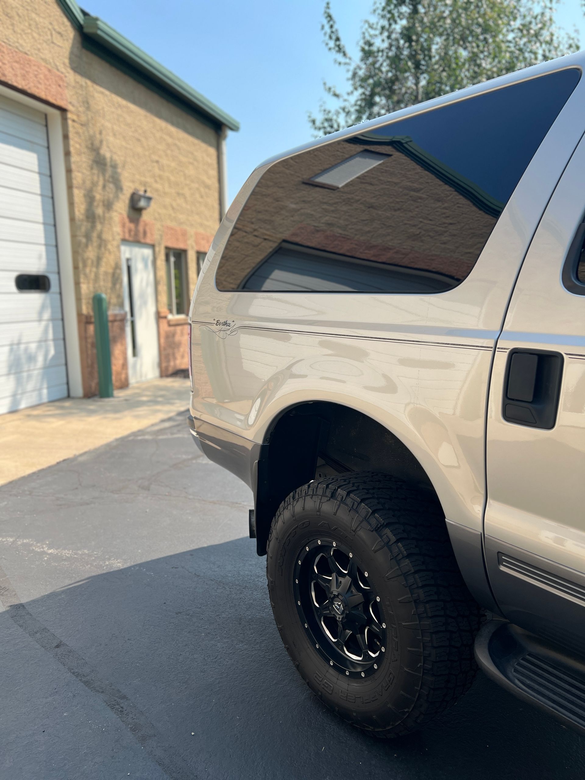 White lifted SUV parked beside a brick building in a sunny lot
