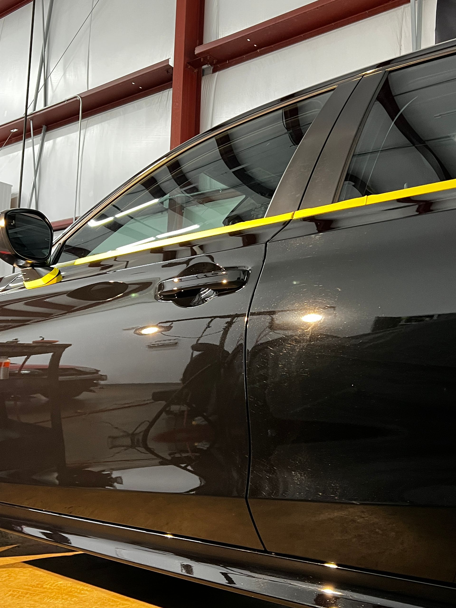 Dark car side with yellow caution tape in a garage or workshop