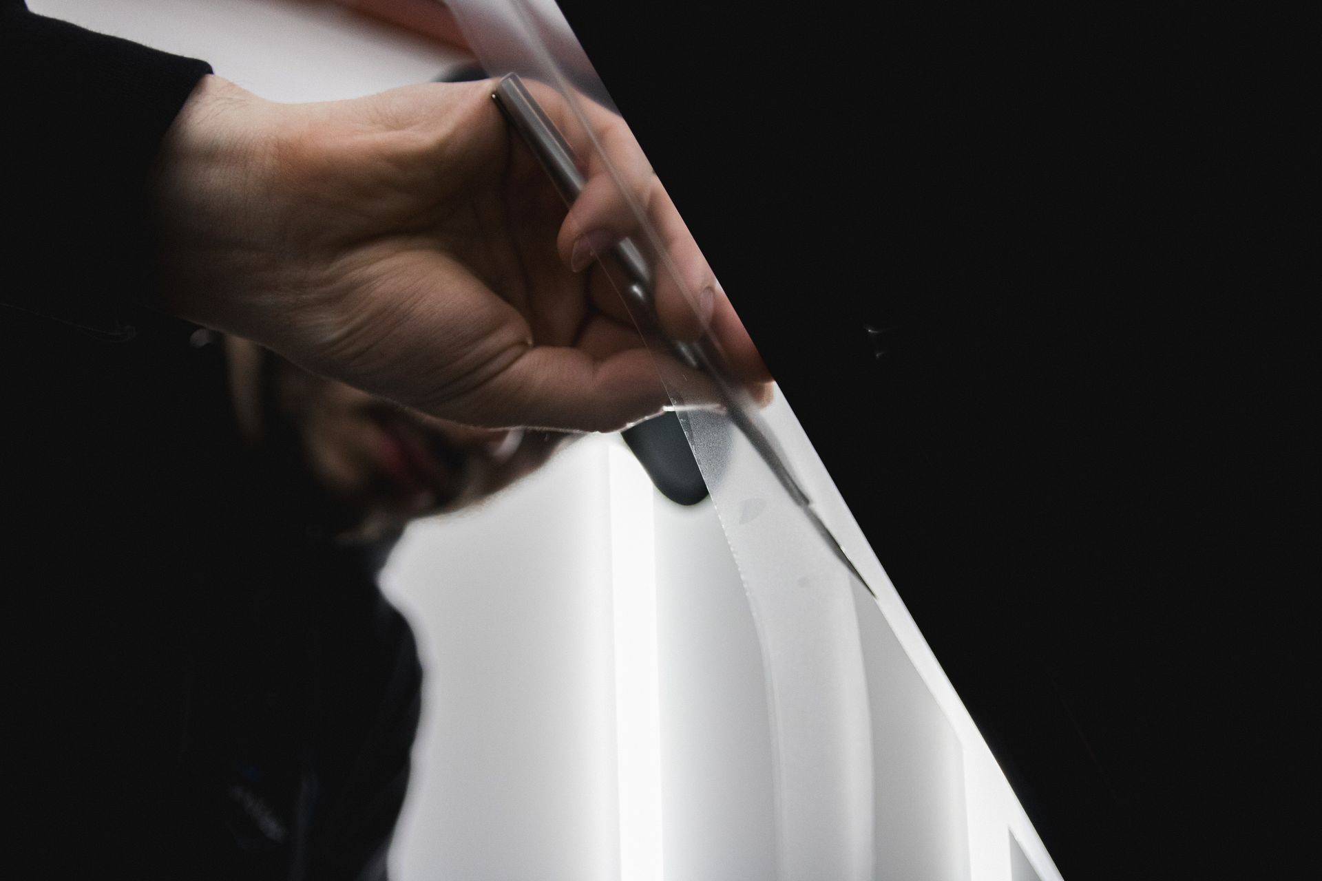 Hand holding a pen over a blank white page against a dark background