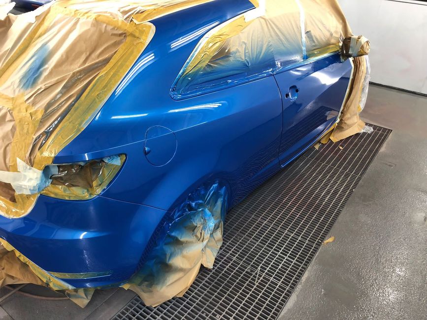 a blue car is being painted in a garage