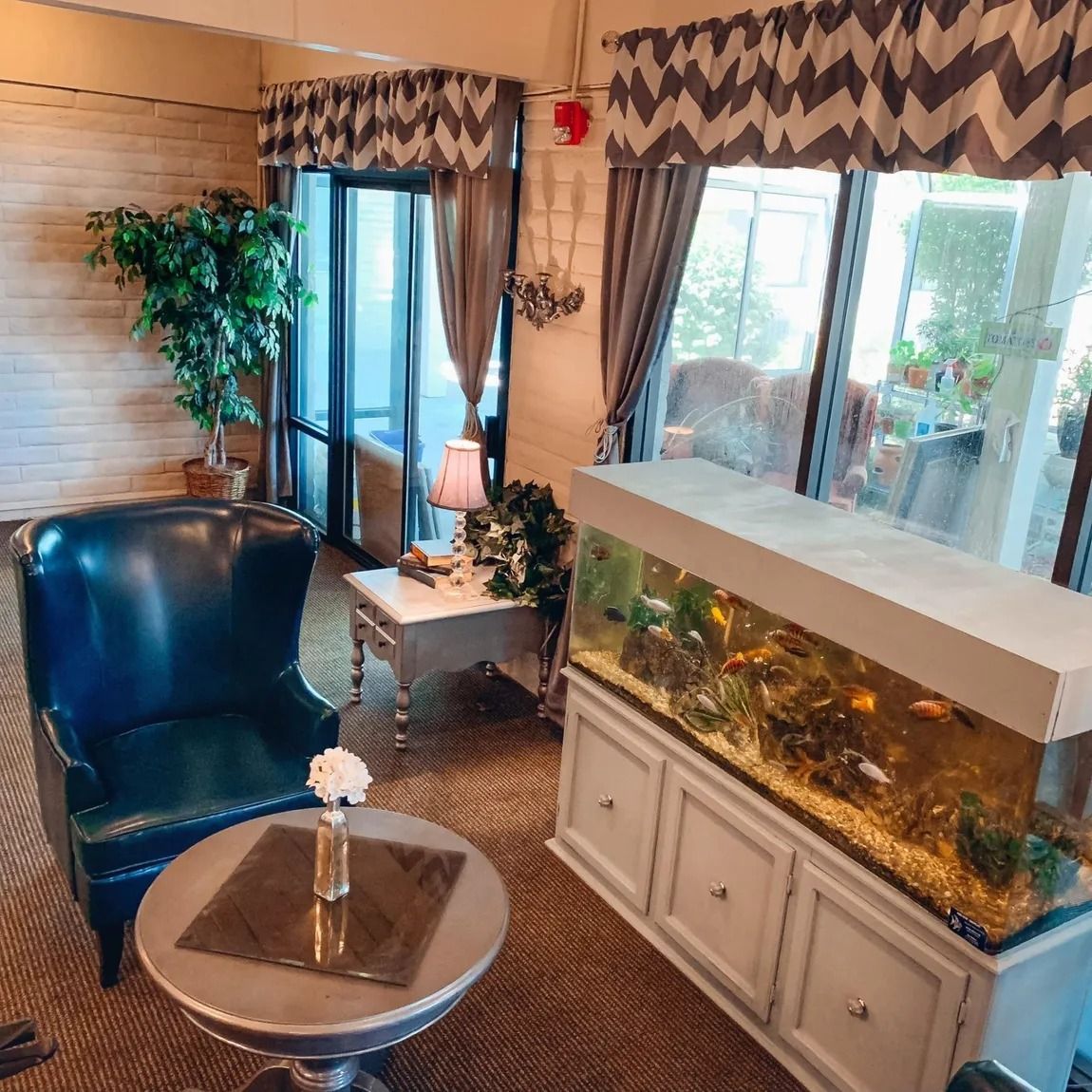 A living room with a chair , table , and aquarium.