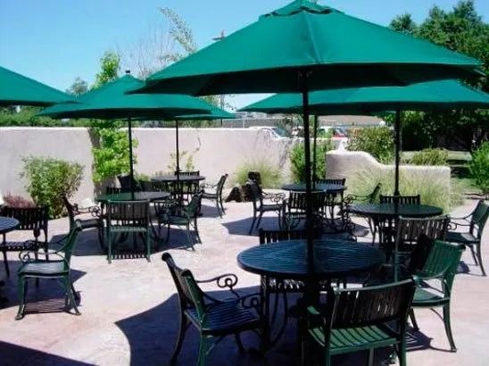 A patio with tables and chairs and green umbrellas