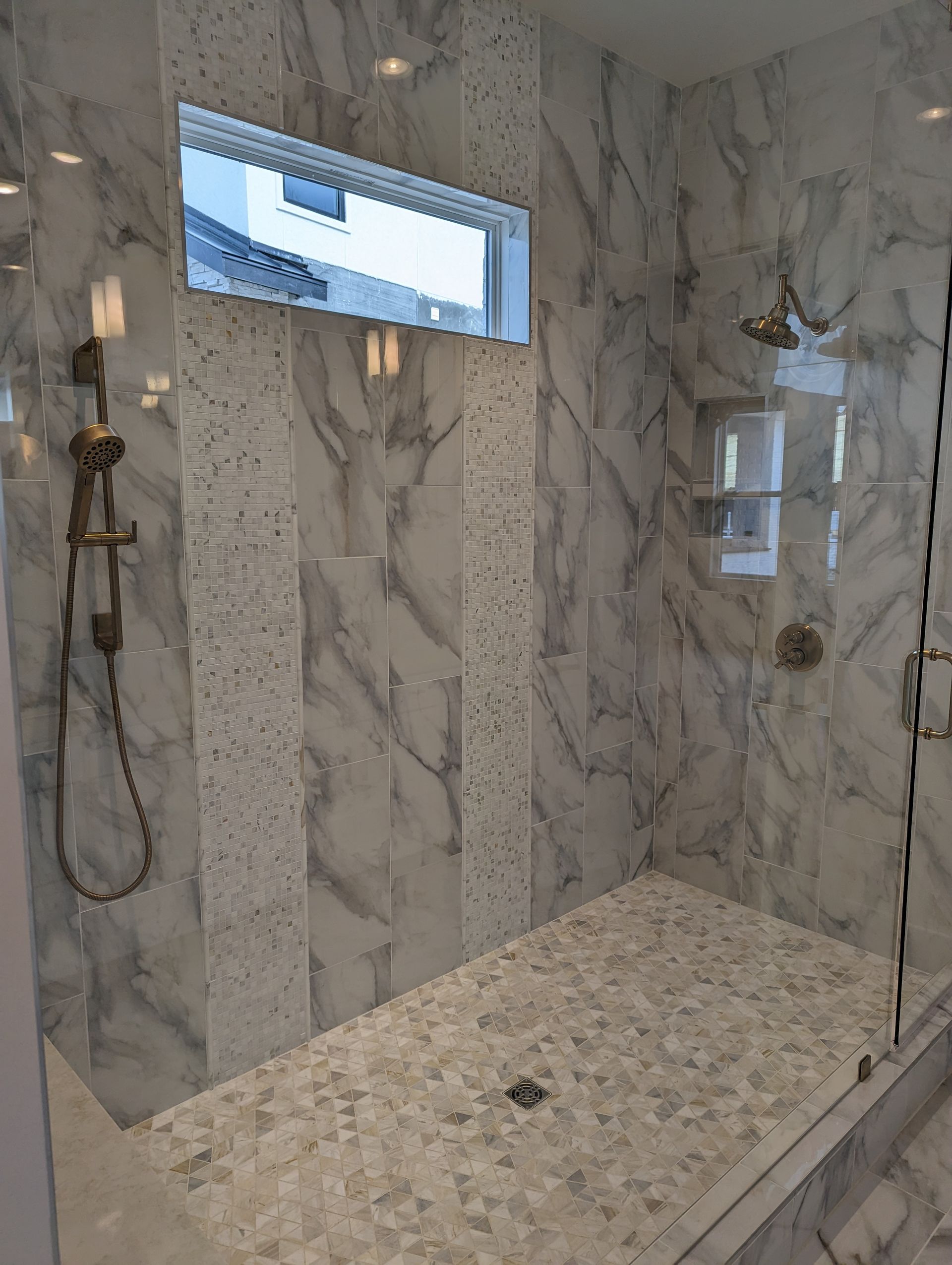 A bathroom with a walk in shower and a window.