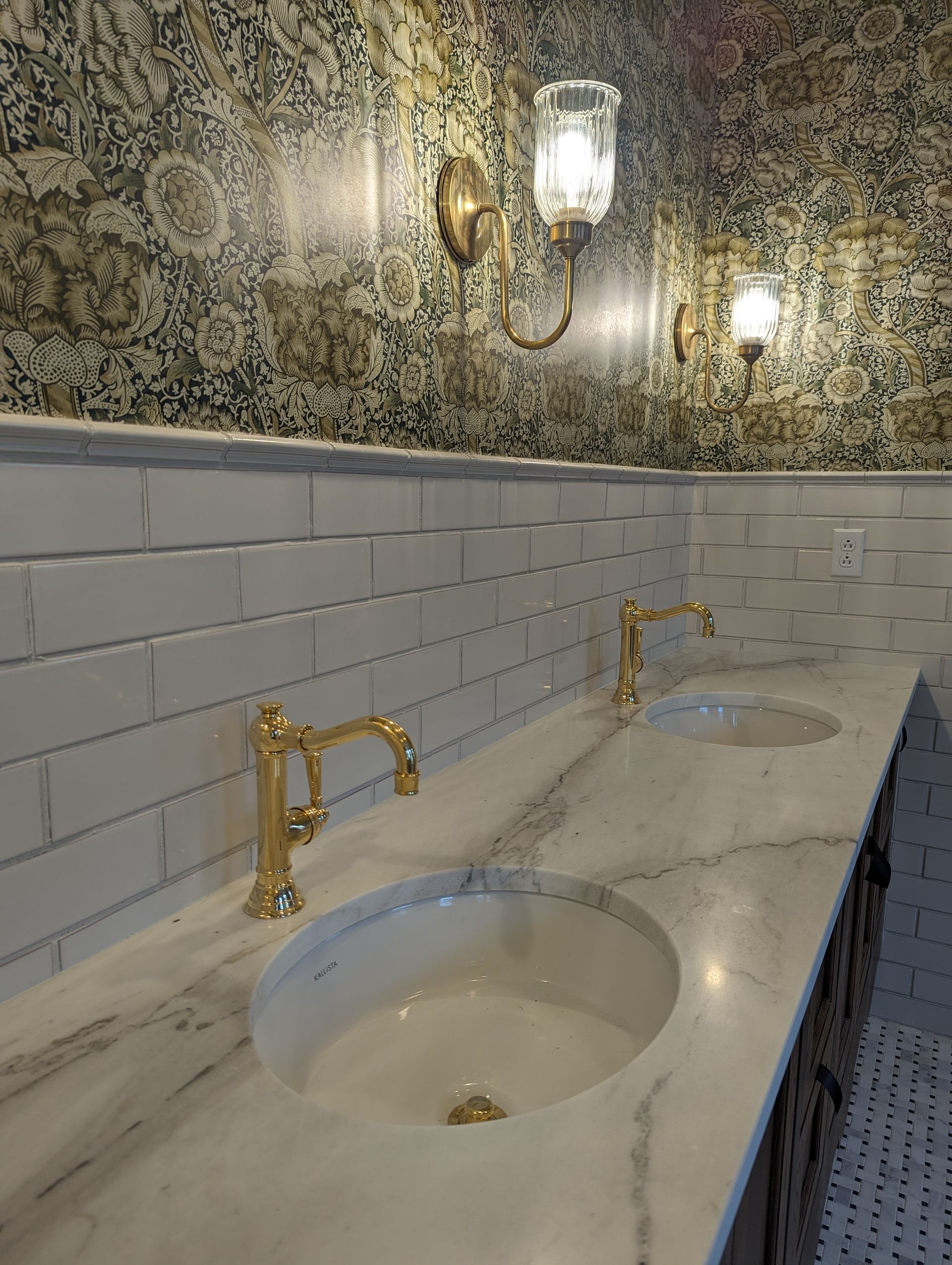 A bathroom with two sinks and two lights on the wall.