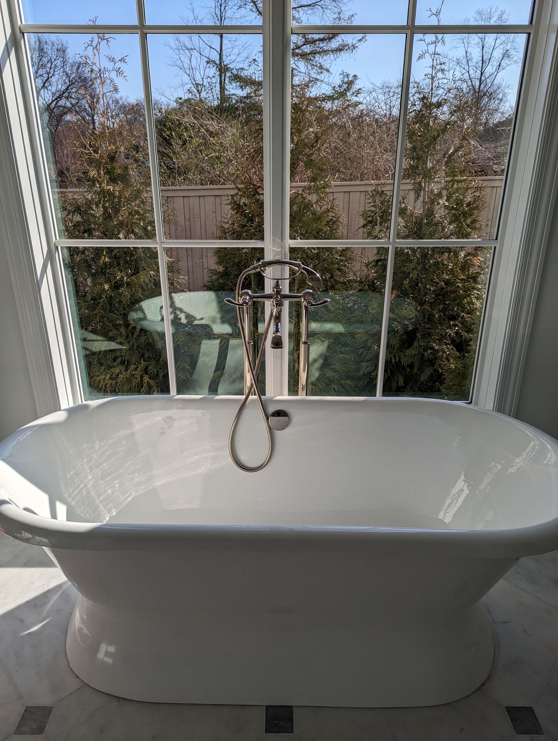 A bathtub is sitting in front of a window in a bathroom.
