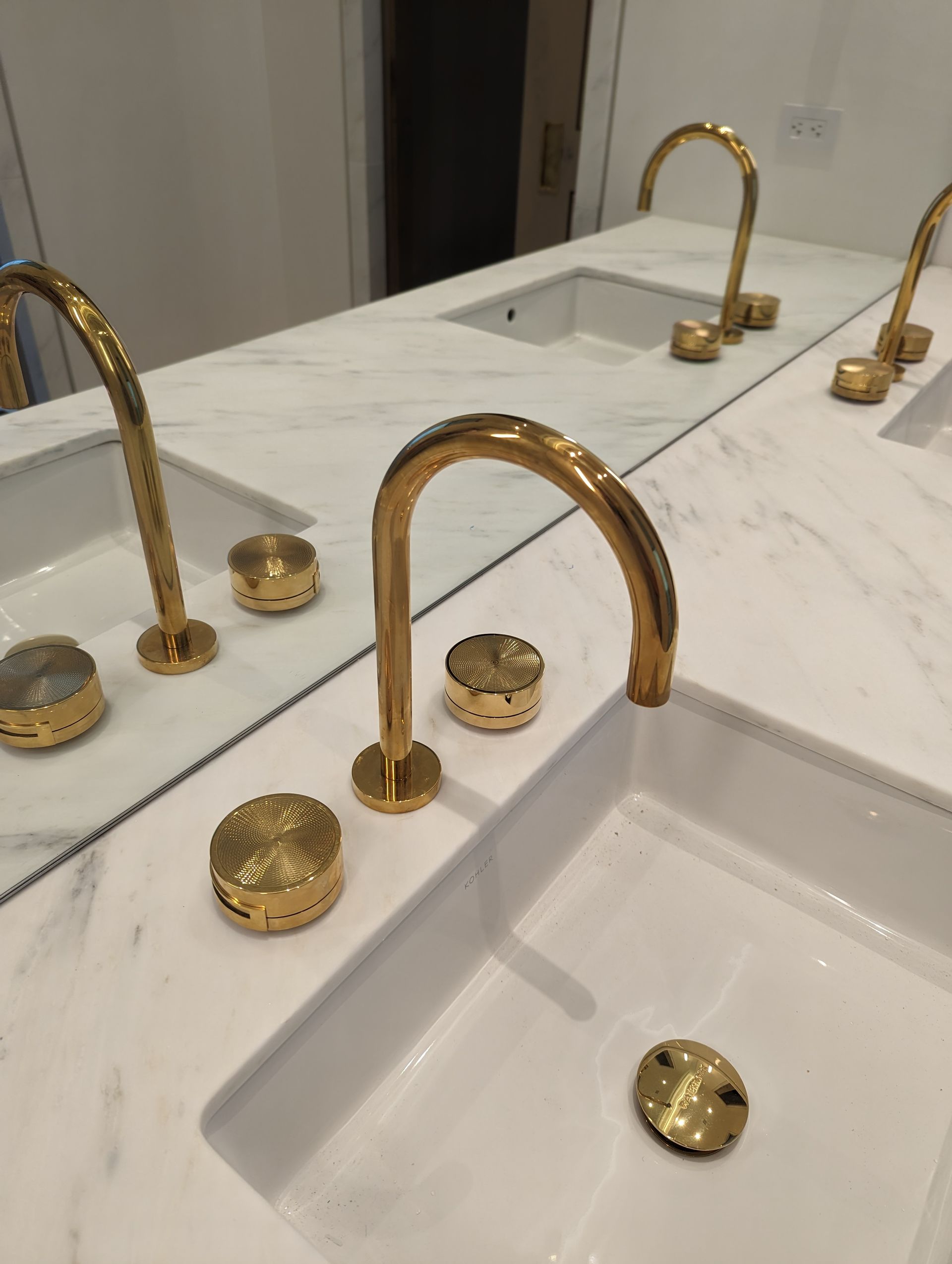 A bathroom sink with gold faucets and a mirror.